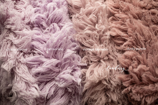 Close-up of fluffy flokati in various shades labeled 'chaise mauve', 'periwinkle', 'vintage lavender', 'dusty purple'